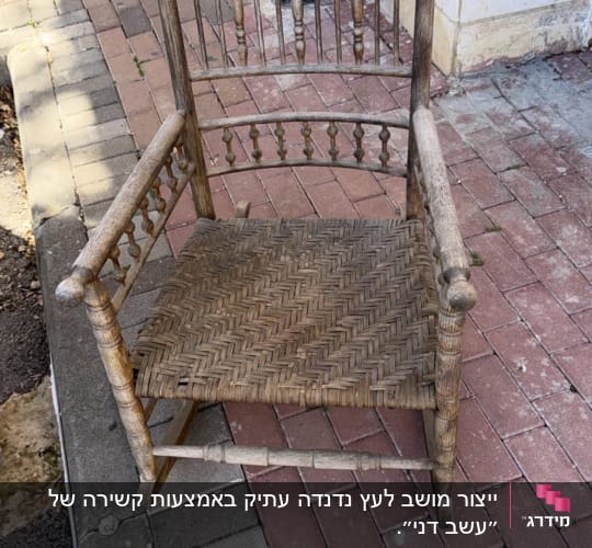 כיסא עץ ישן על מדרכה ליד קיר בניין